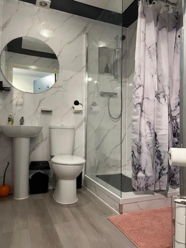 a bathroom with a shower and a toilet and a sink at Crescent Apartment - Two bedroom in Goodmayes