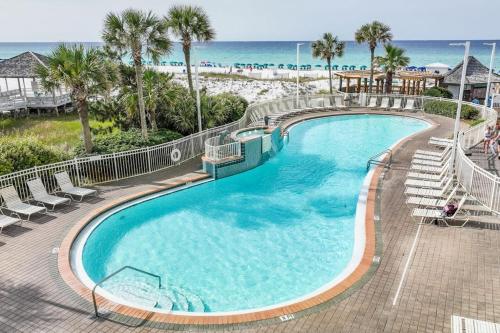 a large swimming pool with chairs and the beach at Pelican Beach Resort 502 in Destin