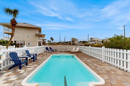a swimming pool with chairs and a white fence at Sunset & Smiles in St. George Island