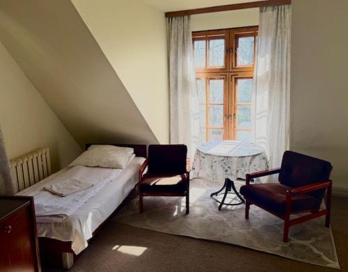 a bedroom with a bed and two chairs and a window at Zajazd Rybaki in Płock