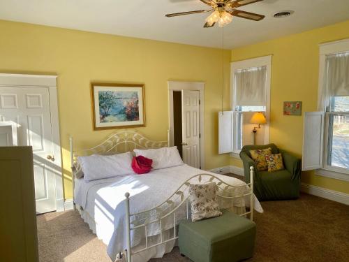 a bedroom with a white bed and a green chair at Red Rose Inn Bed and Breakfast in Bardstown