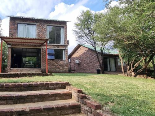 a brick house with stairs in front of a yard at Bloemhof Riverside Chalets in Bloemhof