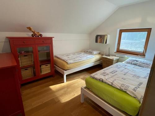 a bedroom with two beds and a dresser and a window at Zbilje Lake house in Medvode