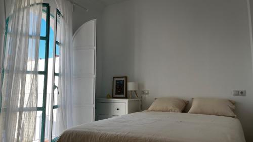 a white bedroom with a bed and a window at Villa Alhelí del Aljarafe in Mairena del Aljarafe