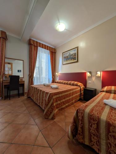 a hotel room with two beds and a desk at Alessandro Palace & Bar in Rome