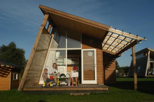 a woman and two children sitting at a table in front of a house at Dancamps Kolding City in Kolding