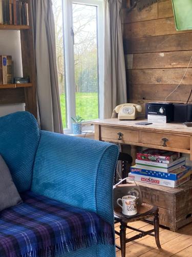 a room with a chair and a desk with books at The Old Apple Shed cosy heated cottage in a meadow close to the charming village of Bethersden in Ashford