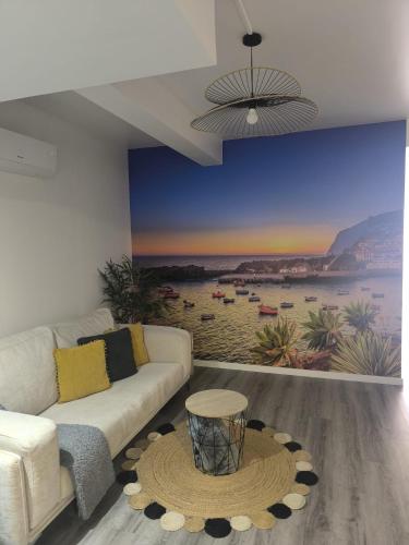 a living room with a couch and a painting of a beach at Cris Place in Câmara de Lobos