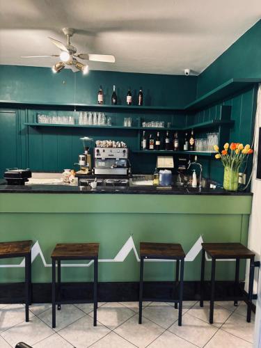 a green kitchen with three stools in front of a counter at Camping Baldo in Brenzone sul Garda