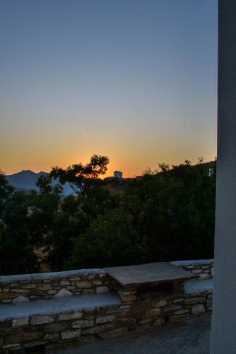 a sunset over a hill with a stone bench at Anéza house tinos in Skaládhos