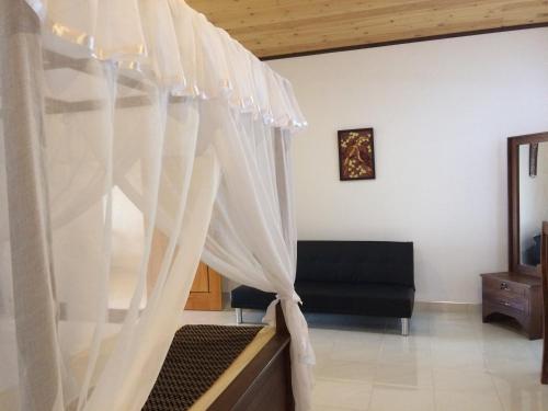 a bedroom with a bed with white curtains at GG Lodge Mirissa in Mirissa