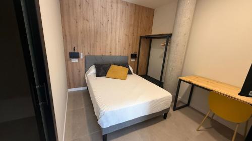 a small bedroom with a bed and a mirror at Bormujos Suites Sevilla in Bormujos