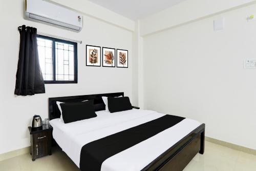 a bedroom with a large white bed with black pillows at Super Hotel O Kadam Ghat Near Ashok RajPath in Patna