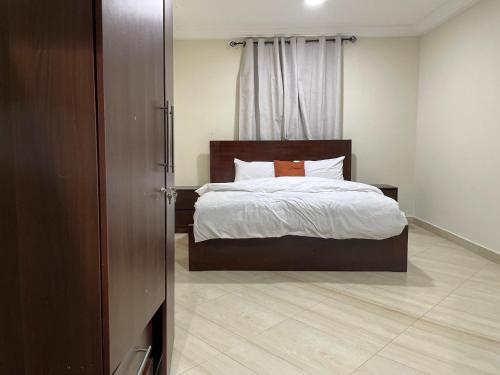 a bedroom with a bed with white sheets and orange pillows at ENA Apartments in Apenkwa