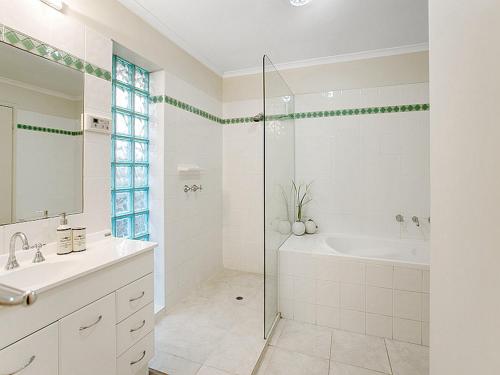 a white bathroom with a shower and a tub and a sink at Isle of Serenity in Frankston