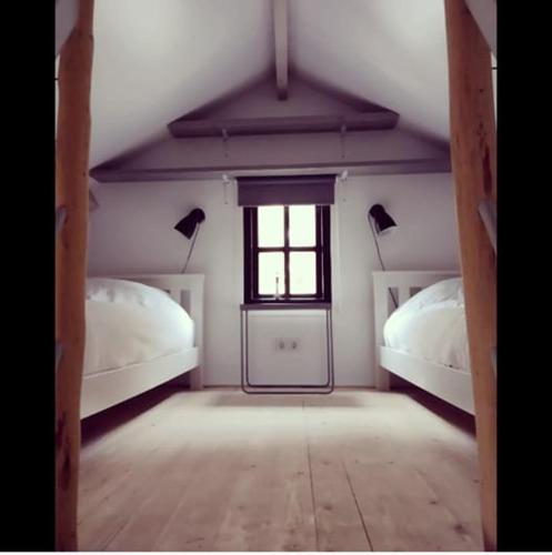 pokój na poddaszu z dwoma łóżkami i oknem w obiekcie Tiny house Weerdinge w mieście Emmen