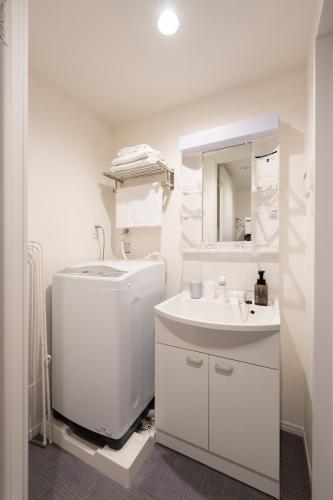 a white bathroom with a sink and a mirror at stella stay in Imari