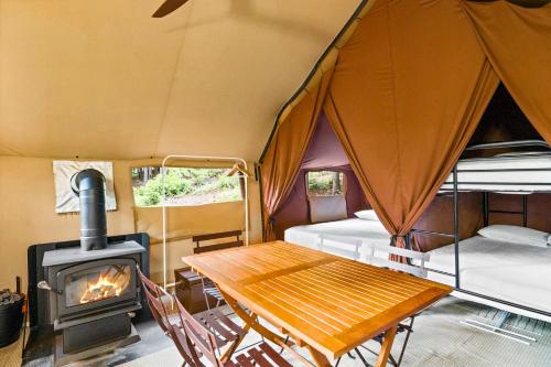 a room with a table and a wood stove at Huttopia Berkshires in Hancock