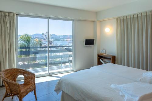 a hotel room with a bed and a large window at Es Mitjorn Hotel in San Antonio