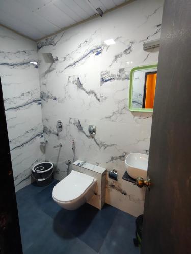 a white bathroom with a sink and a toilet at Hotel Regal Gate in Mumbai