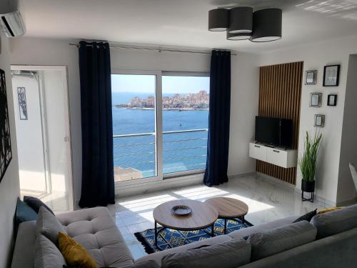 un soggiorno con un divano, un tavolo e una grande finestra di Stella Apartment a Sarandë