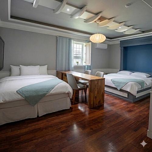 a bedroom with two beds and a desk and a table at Hiddenhill Bulkuksa Hotel in Gyeongju