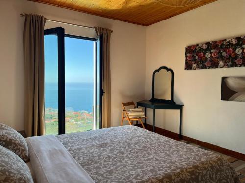 a bedroom with a bed and a view of the ocean at Casa Vista do Ledo in Arco da Calheta