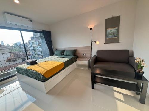 a bedroom with a bed and a chair and a window at 4 mins to MRT Sutthisan in Bangkok