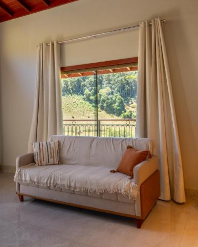 a couch in a room with a large window at Chalé Estalagem Sítio Sossego in Domingos Martins