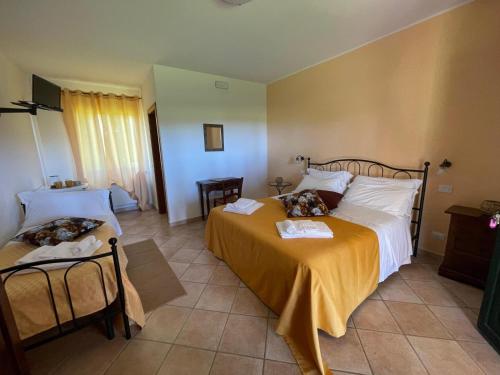 a bedroom with two beds and a yellow blanket at Agriturismo Valle Martina in Saturnia