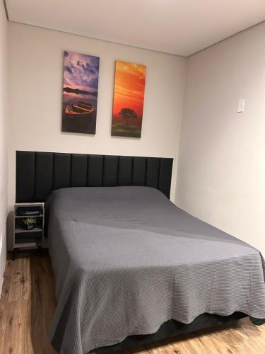 a bedroom with a bed with three paintings on the wall at Studio 01 JD Paulistano in Ribeirão Preto