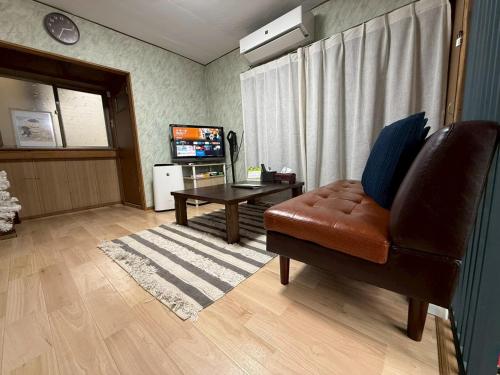 a living room with a leather chair and a table at Okayama Urban Peach in Okayama