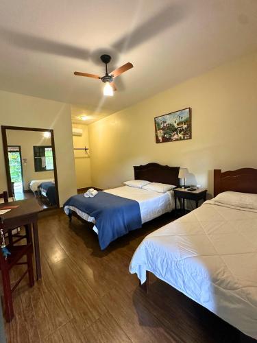 a hotel room with two beds and a ceiling fan at Pousada Arara in Valença