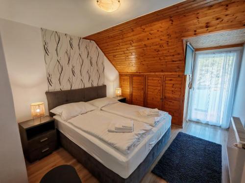 a bedroom with a bed in a room with a window at Beta Apartman in Bük