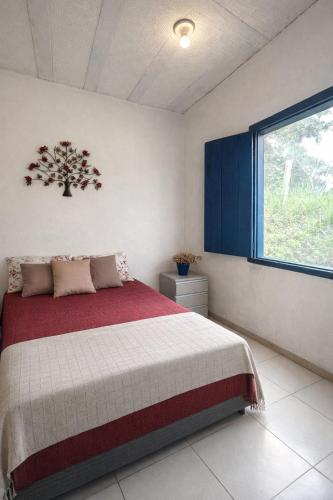 a bedroom with a bed with a red blanket and a window at Sonho de Minas Hospedaria in Ouro Preto
