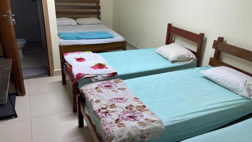 a room with three beds with towels on them at Pousada Centro Oeste in Trindade