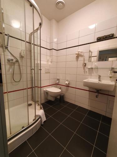 a bathroom with a shower and a toilet and a sink at Hotel Galaxie in Zlín