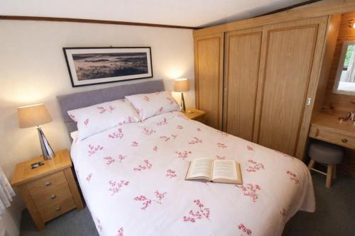 a bedroom with a bed with a book on it at Neaum Crag Lodge ideal for a couple or family with young children in a woodland setting at Skelwith Bridge in Grasmere