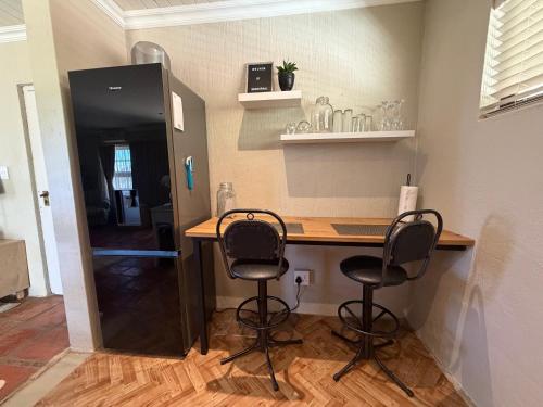 a kitchen with a counter with two chairs and a table at Windkraal Farm Studio in Bonnievale