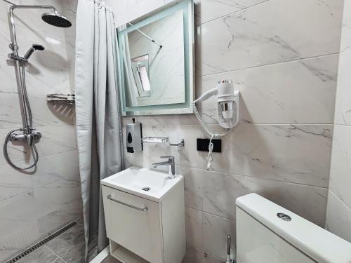 a white bathroom with a sink and a mirror at Old Friend Guest House in Berehove