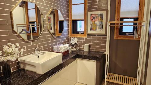 a bathroom with a sink and some mirrors at Picasso Guesthouse in Mokpo