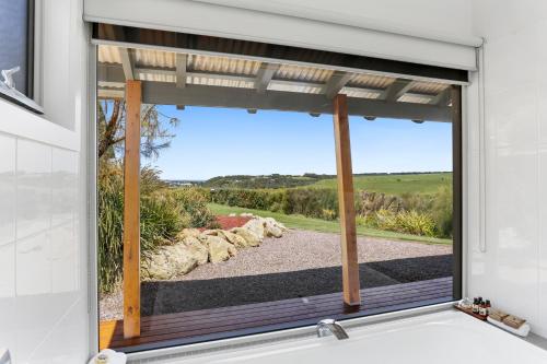 a bathroom window with a view of a yard at Anchors Port Campbell in Port Campbell