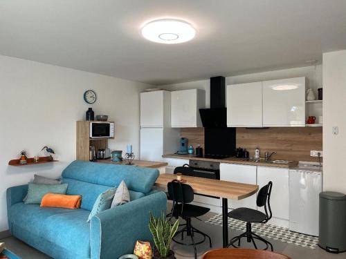 a living room with a blue couch and a kitchen at Casanella in Le Hézo