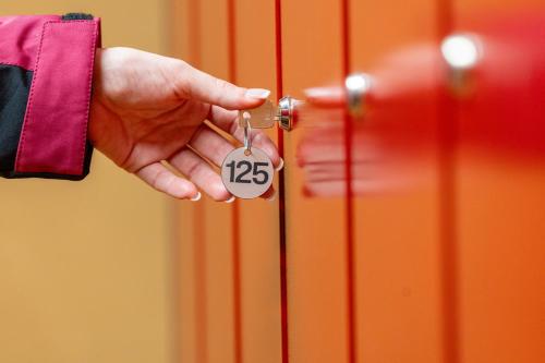 a person holding a key in a door at Hotel Alaska Cortina in Cortina dʼAmpezzo