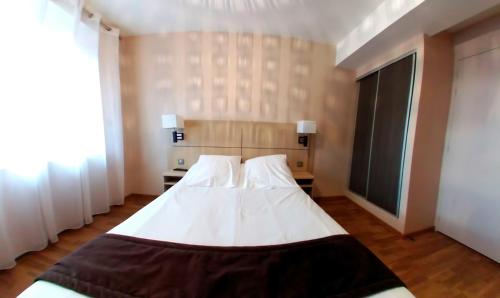 a bedroom with a large white bed with two pillows at Hotel Au Bon Coin in Cloyes-sur-le-Loir