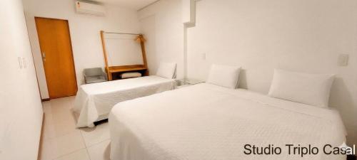a white room with two beds and a mirror at Starlis Home - Versátil in Cuiabá