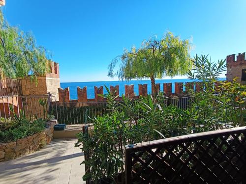 a fence with trees and the ocean in the background at Appartamenti Castello Borelli in Borghetto Santo Spirito