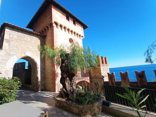 a building with a tree next to a fence at Appartamenti Castello Borelli in Borghetto Santo Spirito