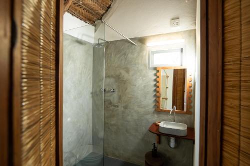 a bathroom with a shower with a sink and a mirror at Tofo Beach Gardens in Inhambane