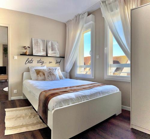 a bedroom with a large bed and two windows at Pearly EuroPoint in Saint-Louis